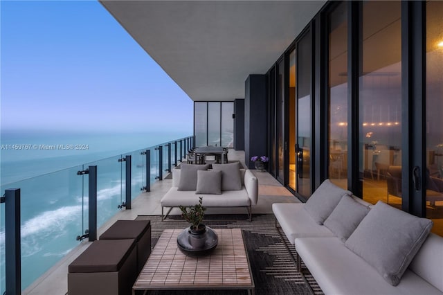 balcony at dusk featuring a water view and an outdoor living space