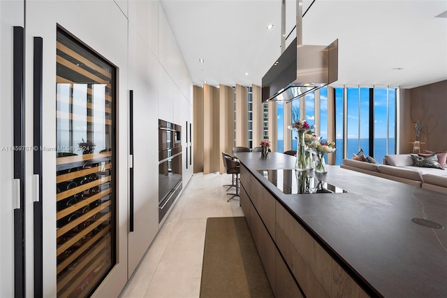 kitchen with expansive windows, black electric cooktop, beverage cooler, white cabinets, and a water view