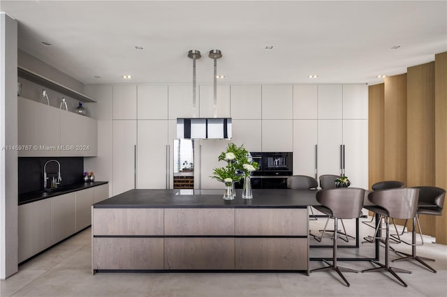 kitchen with a breakfast bar, white cabinetry, white fridge, and a center island