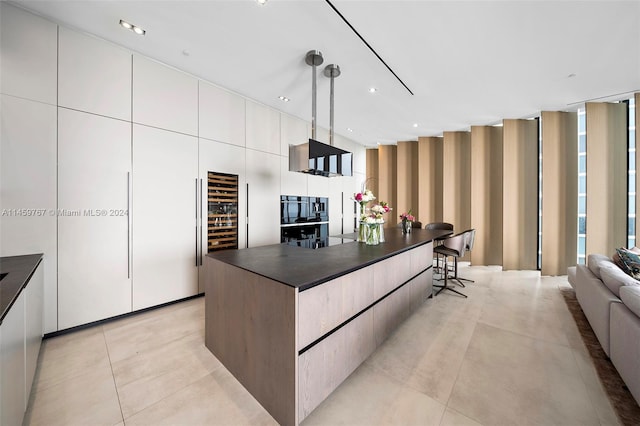 kitchen with light tile floors, a kitchen breakfast bar, white cabinets, decorative light fixtures, and a center island