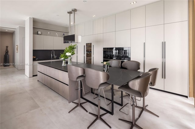 kitchen featuring oven, a kitchen breakfast bar, sink, an island with sink, and light tile floors