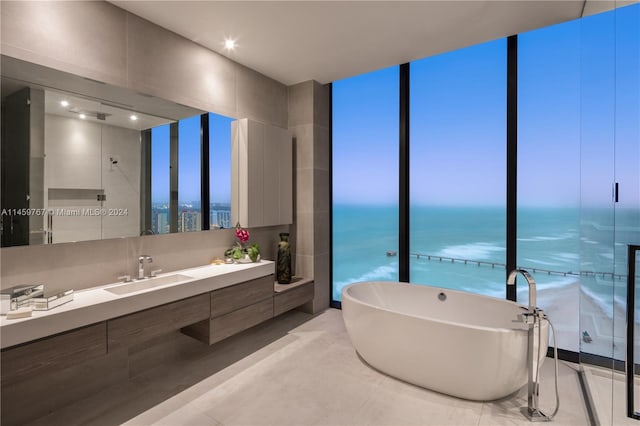 bathroom with a bath to relax in, tile flooring, oversized vanity, and a water view