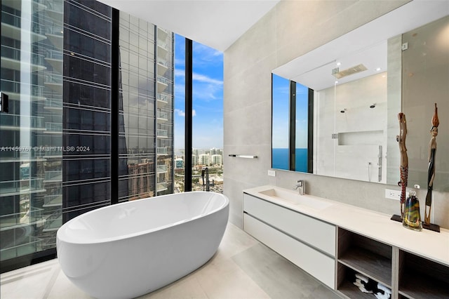 bathroom with tile walls, tile floors, a bath, and vanity