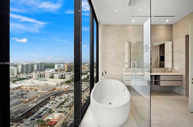 bathroom with tile walls, a bath, and vanity