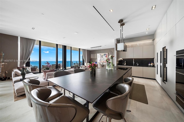 dining area with expansive windows, light tile flooring, and a water view