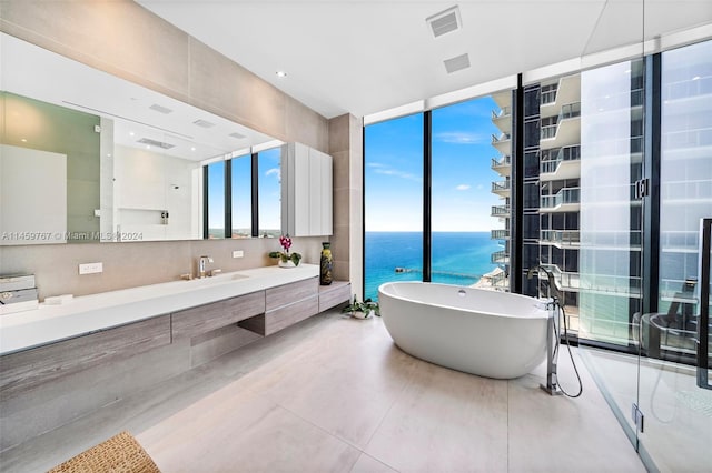 bathroom with a washtub, floor to ceiling windows, tile flooring, a water view, and vanity