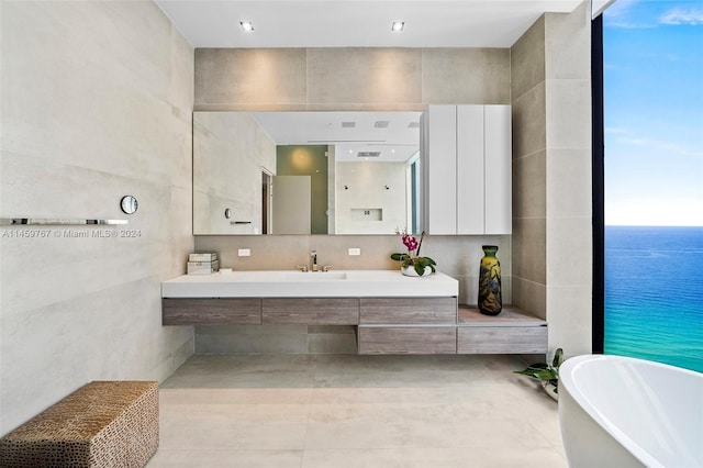 bathroom featuring vanity, a water view, a wealth of natural light, and tile walls