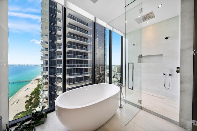 bathroom featuring a water view, a bath to relax in, and tile flooring