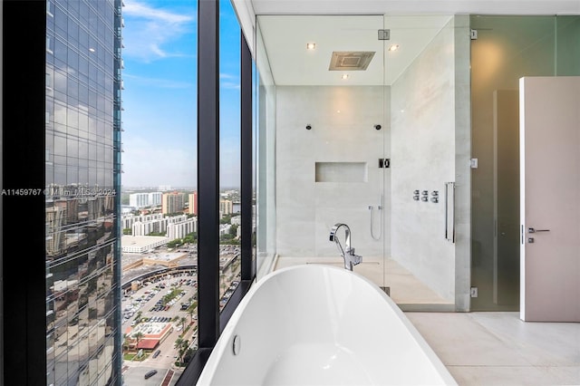 bathroom featuring a bath to relax in, expansive windows, and tile floors