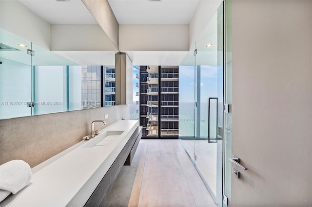 bathroom featuring double sink, walk in shower, expansive windows, and oversized vanity