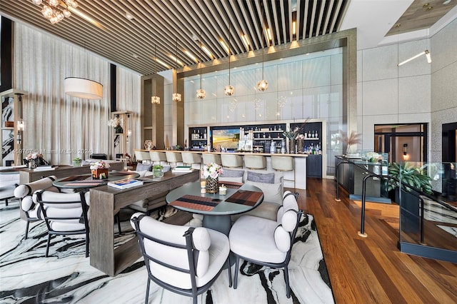 dining space featuring a notable chandelier, dark wood-type flooring, and a towering ceiling