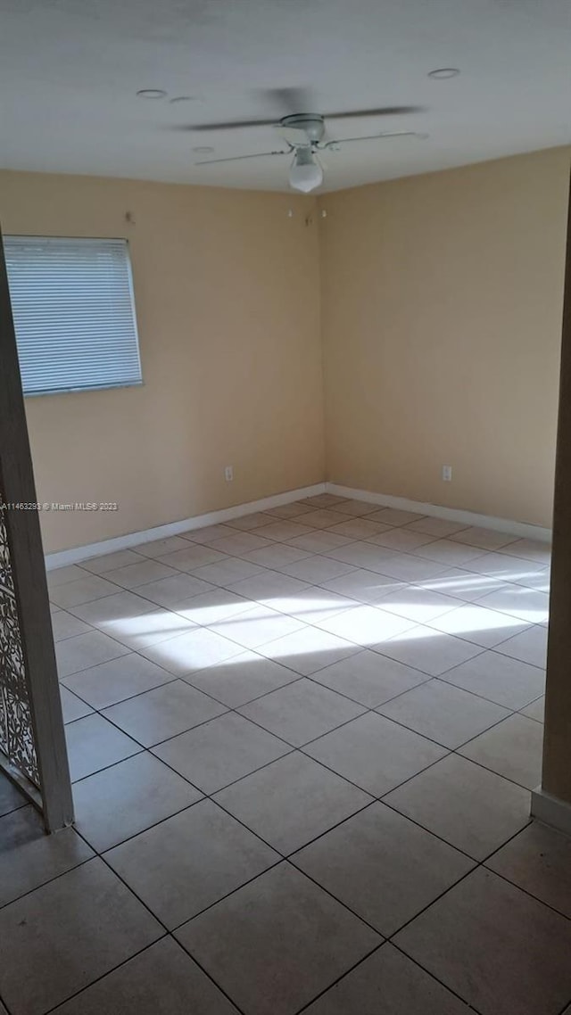 spare room featuring light tile floors and ceiling fan