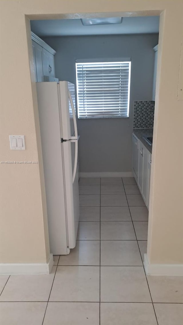 kitchen with light tile floors, white cabinets, and white refrigerator