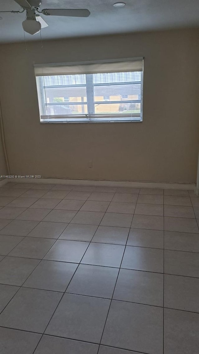 tiled empty room with ceiling fan and a wealth of natural light