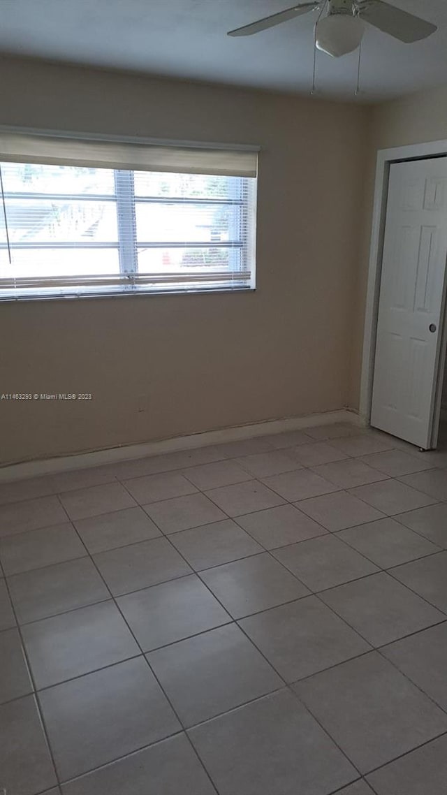 empty room with light tile floors, ceiling fan, and a wealth of natural light