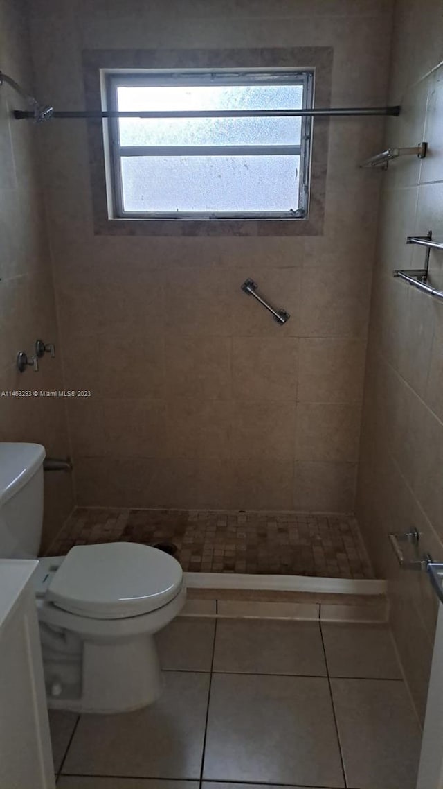 bathroom featuring tile flooring, toilet, and tiled shower