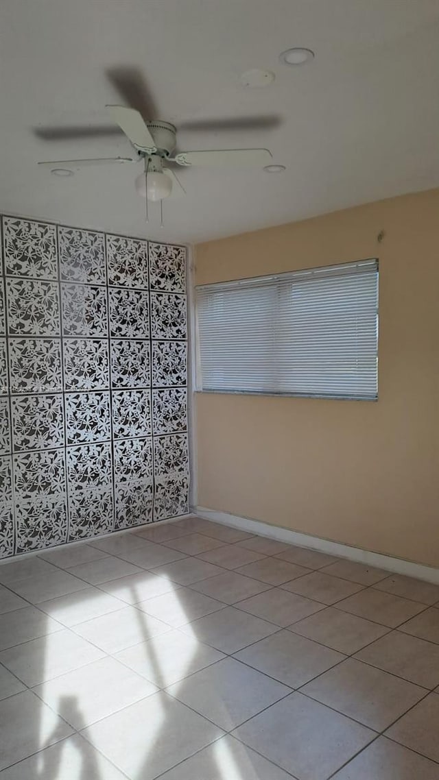 tiled empty room featuring ceiling fan