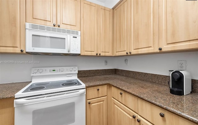 kitchen featuring white appliances, light brown cabinets, and dark stone counters