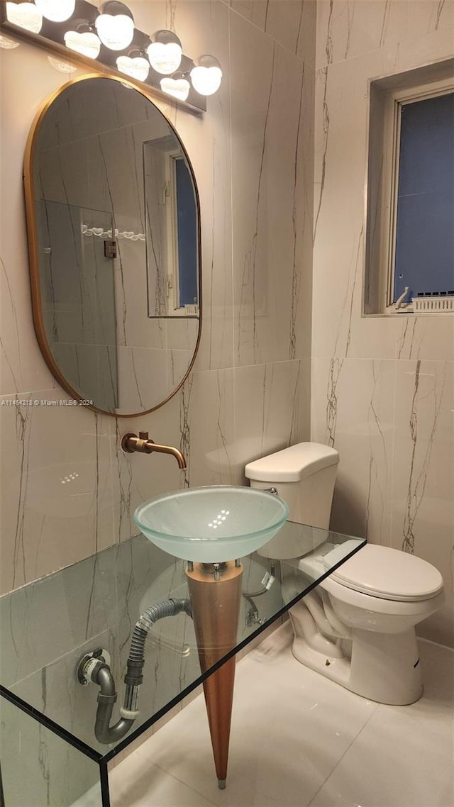 bathroom with toilet, tile patterned floors, and tile walls