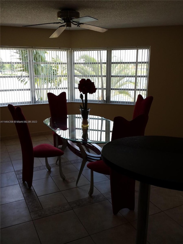 tiled dining space with a textured ceiling and ceiling fan