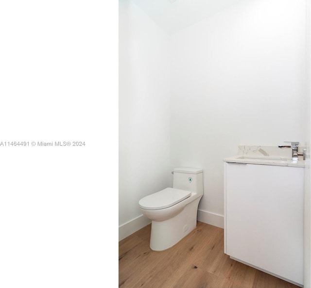 bathroom with toilet, vanity, and hardwood / wood-style flooring