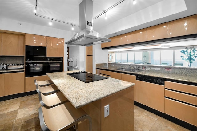 kitchen featuring island range hood, a healthy amount of sunlight, a breakfast bar area, black appliances, and a center island