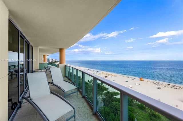 balcony with a water view and a view of the beach