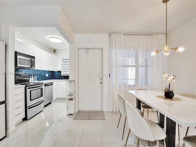 kitchen with white cabinetry, light tile flooring, stainless steel appliances, tasteful backsplash, and pendant lighting