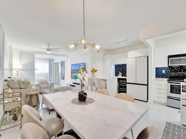 tiled dining area with rail lighting and ceiling fan with notable chandelier