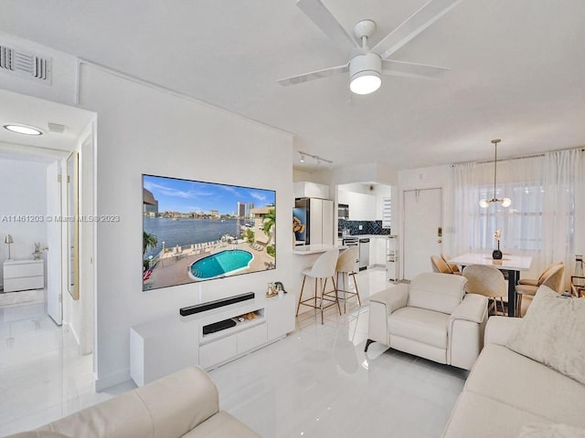 tiled living room featuring ceiling fan with notable chandelier