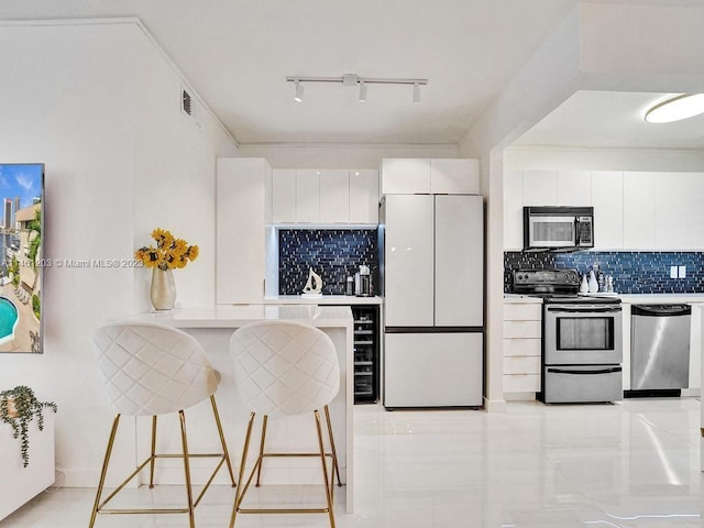 kitchen featuring a breakfast bar, white cabinetry, backsplash, and stainless steel appliances