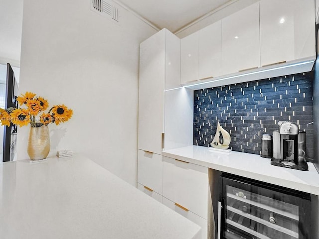 bar featuring wine cooler, tasteful backsplash, and white cabinetry