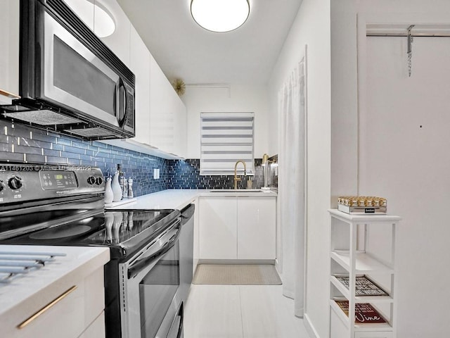 kitchen featuring light tile floors, range with electric cooktop, white cabinets, backsplash, and sink