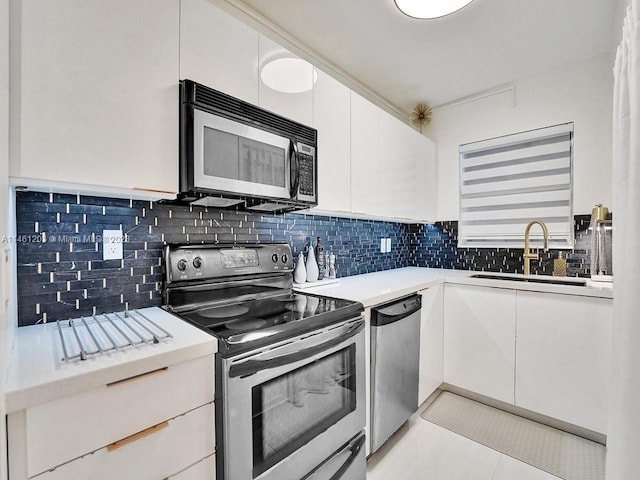 kitchen with appliances with stainless steel finishes, sink, light tile floors, white cabinets, and tasteful backsplash