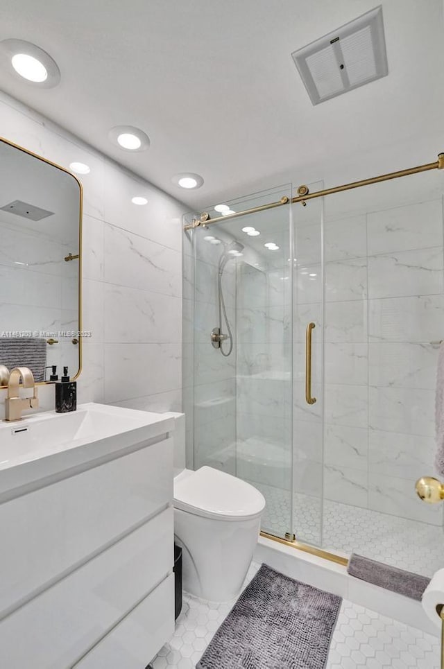 bathroom featuring toilet, large vanity, a shower with door, tile walls, and tile floors