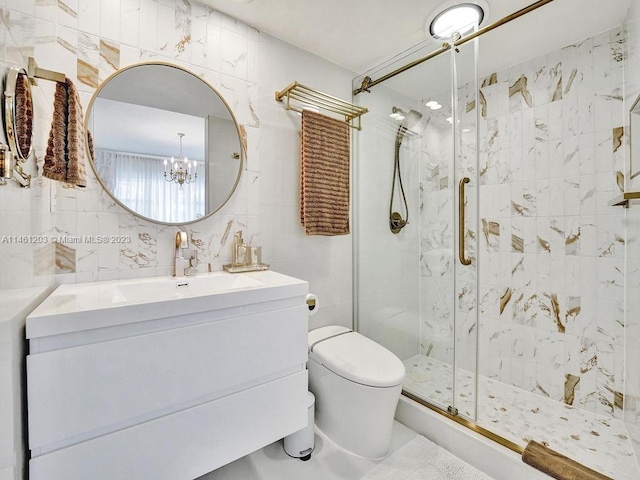 bathroom with a chandelier, toilet, oversized vanity, a shower with door, and tile walls