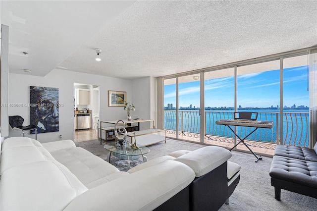 living room with light carpet, a water view, expansive windows, and a textured ceiling