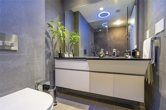 bathroom featuring toilet, tile flooring, oversized vanity, and tile walls