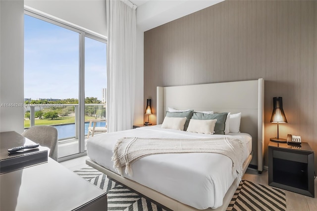 bedroom with a water view, access to outside, and light wood-type flooring