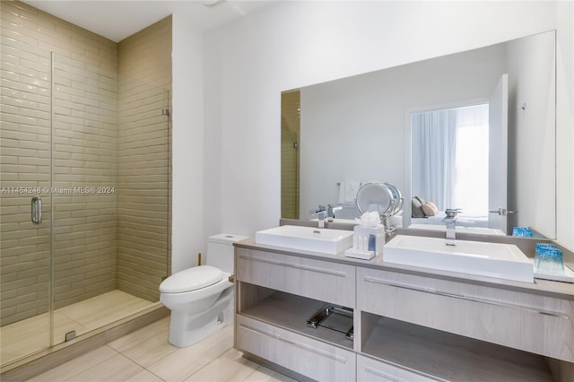 bathroom featuring toilet, vanity with extensive cabinet space, an enclosed shower, dual sinks, and tile flooring