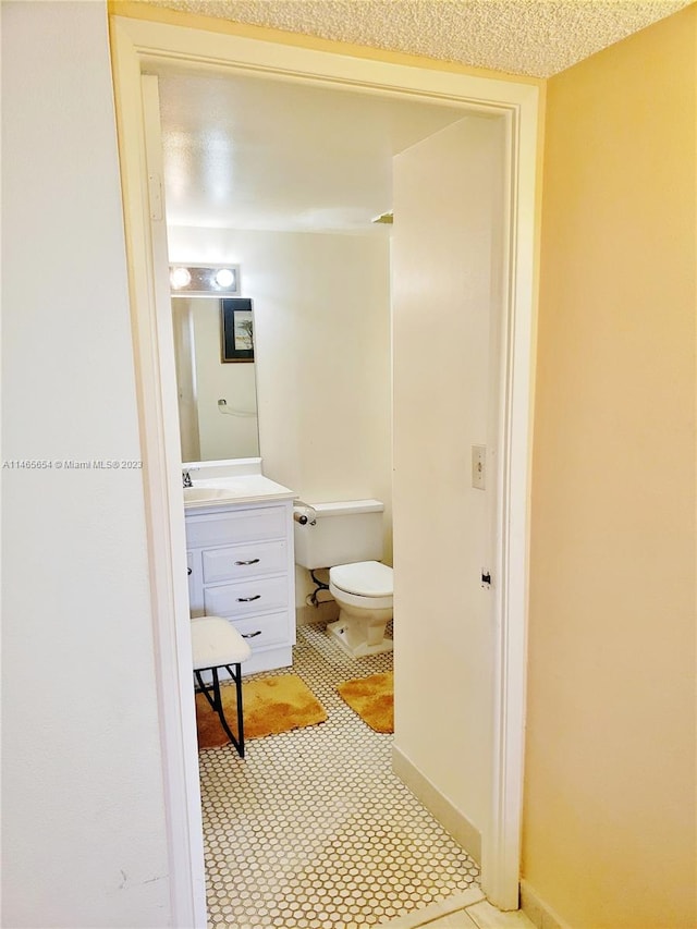 bathroom featuring toilet, tile flooring, a textured ceiling, and vanity