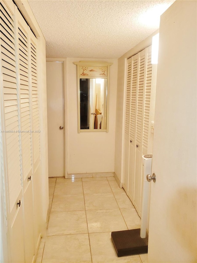 hall with light tile flooring and a textured ceiling