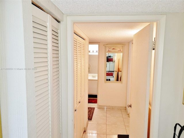 hallway featuring light tile floors and a textured ceiling