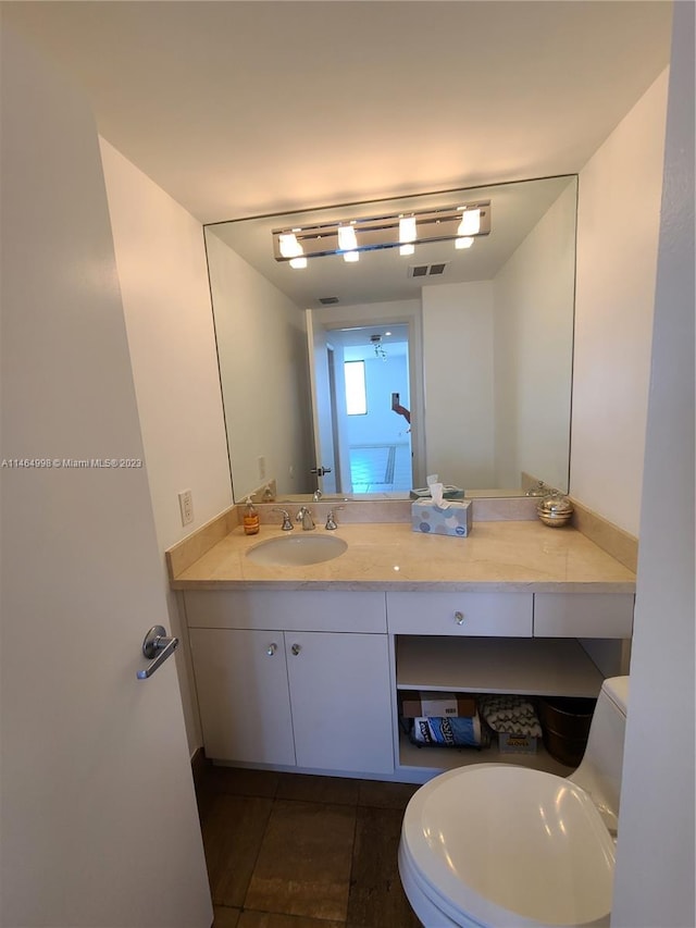 bathroom with toilet, vanity, and tile flooring