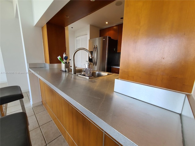 kitchen with stainless steel fridge, stainless steel counters, sink, and light tile floors