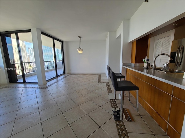 interior space featuring light tile flooring, expansive windows, hanging light fixtures, and stainless steel counters