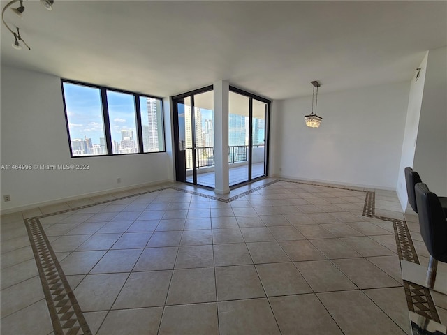 spare room with floor to ceiling windows, light tile floors, and a wealth of natural light