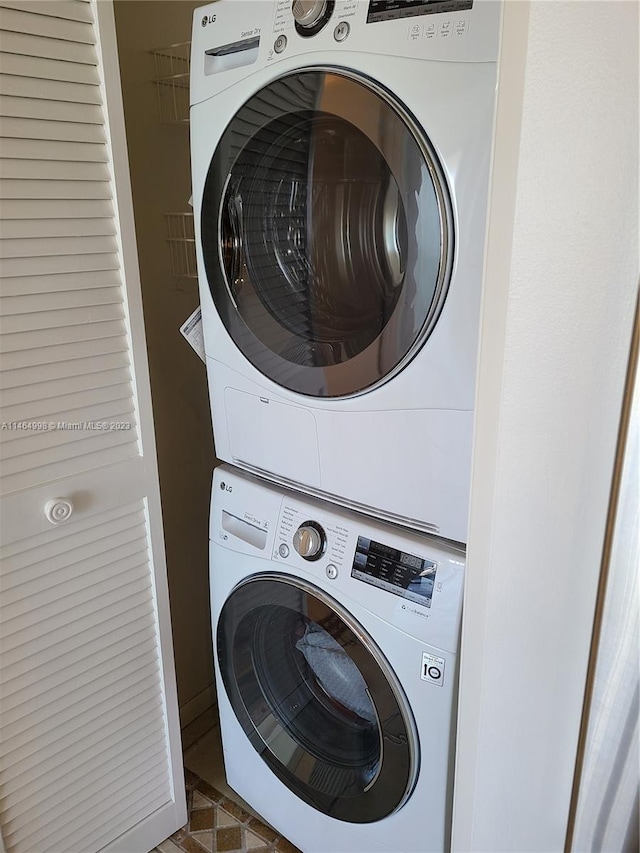 washroom featuring dark tile floors and stacked washing maching and dryer