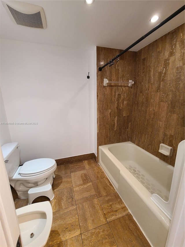 bathroom with a bidet, toilet, tile floors, and tiled shower / bath