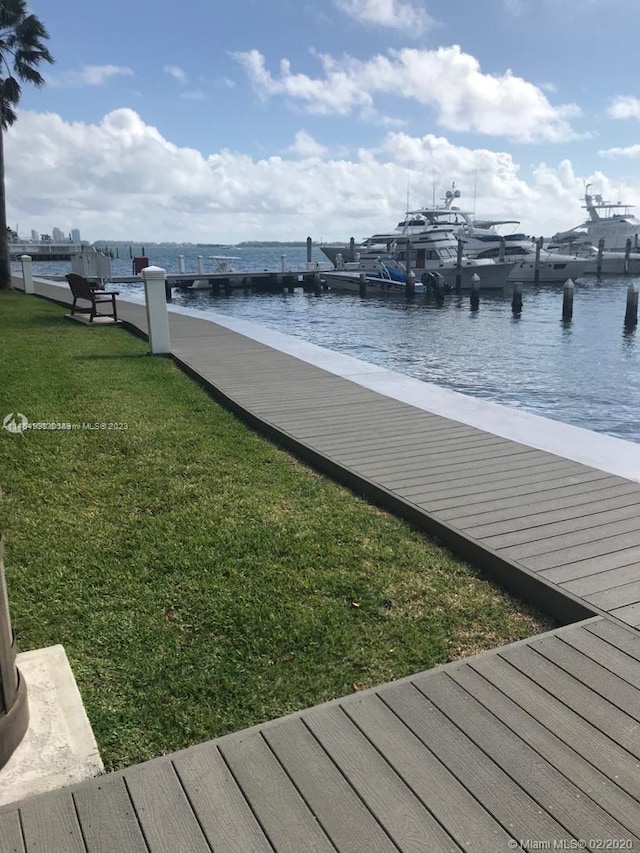 dock area with a lawn and a water view